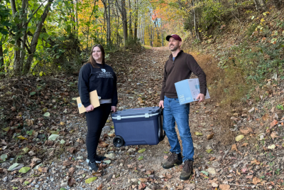 (From left) Beth O'Connell, holding a clipboard, and Alasdair Cohen, holding water testing equipment, outdoors doing field work for their water testing study